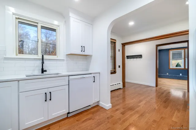 a kitchen with white cabinets and wooden floors