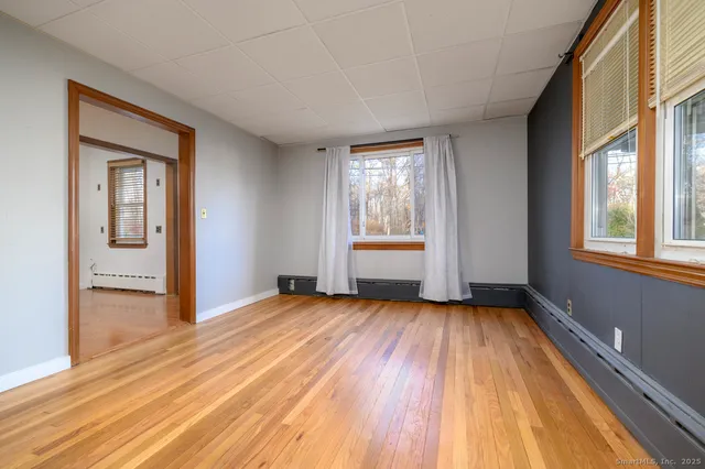 a view of an empty room with a window and wooden floor