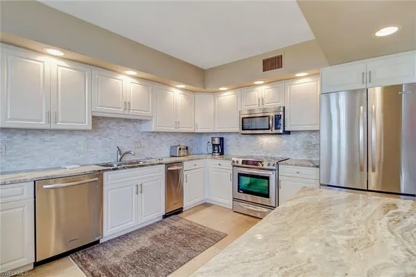 a kitchen with stainless steel appliances granite countertop a sink a stove a microwave and cabinets