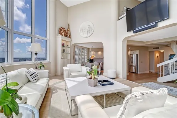 a living room with furniture kitchen view and a window