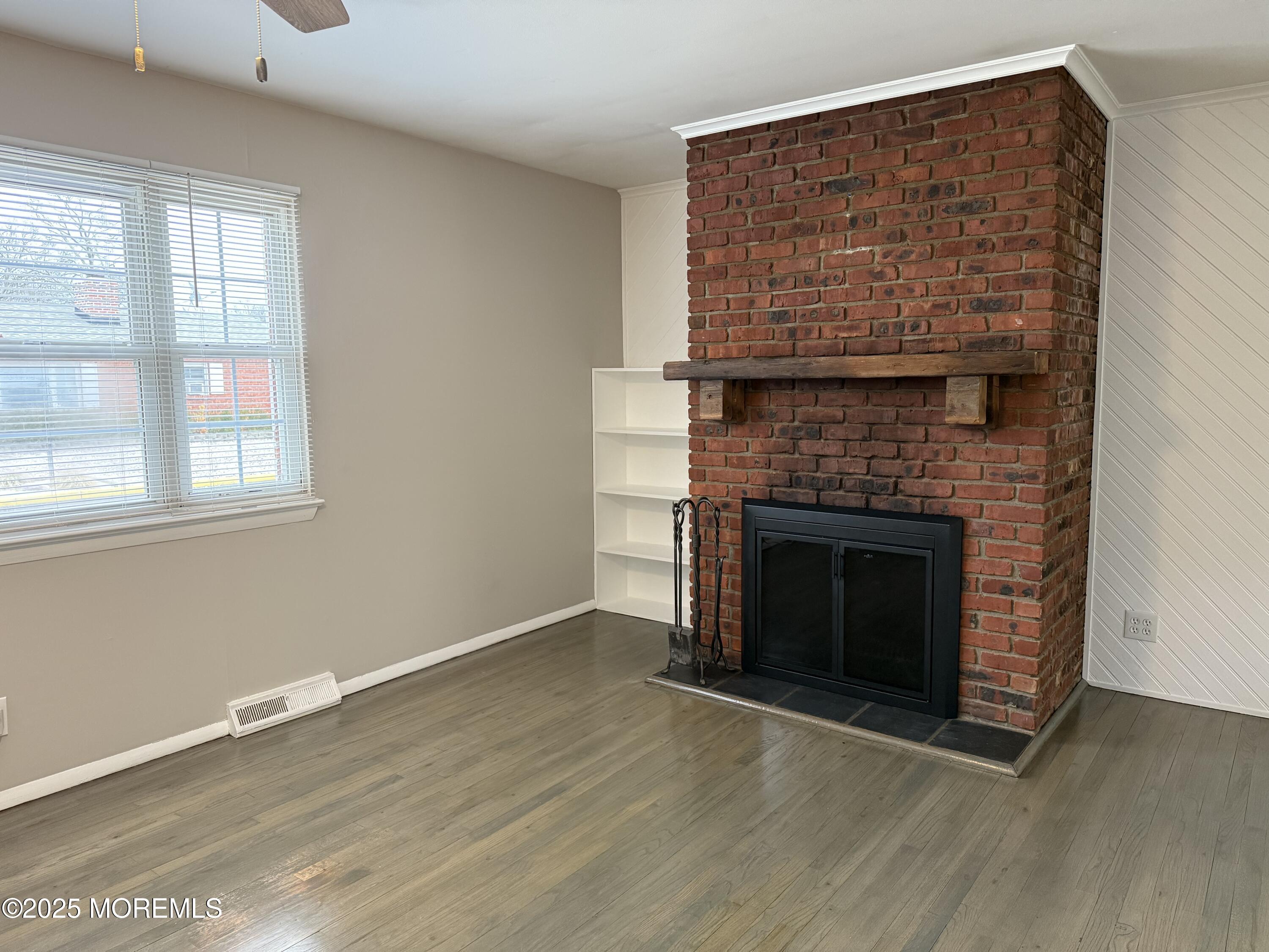 821 Burnt Tavern Road, Unit 6 Point Pleasant, NJ 08742 - Photo 2 of 7 a view of an empty room with wooden floor fireplace and a window