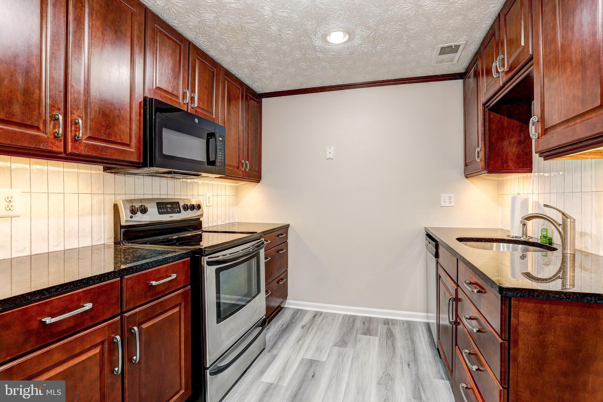 5920 Watch Chain Way, Unit 5106 Columbia, MD 21044 - Photo 8 of 27 a kitchen with granite countertop wooden cabinets stainless steel appliances and a sink