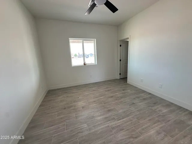 an empty room with chandelier fan and windows