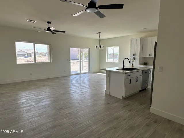 a kitchen with granite countertop a refrigerator a stove a sink and white cabinets