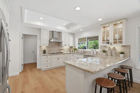 a kitchen with granite countertop sink stove and white cabinets