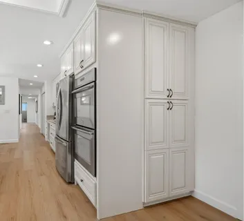 a view of a kitchen with a refrigerator and wooden floor