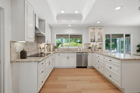 a kitchen with kitchen island granite countertop a sink window and cabinets