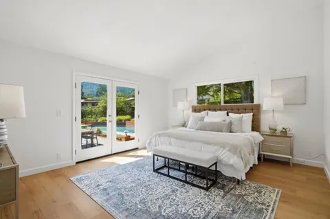 a spacious bedroom with a bed a window and wooden floor