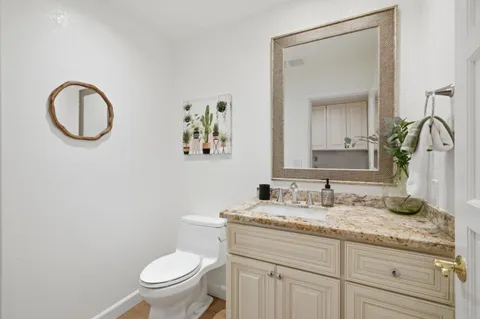 a bathroom with a granite countertop toilet a sink and a mirror