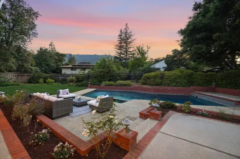 a view of a patio with couches chairs and a fire pit with large trees