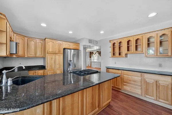 a kitchen with stainless steel appliances granite countertop a sink a stove and a wooden cabinets