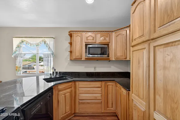a kitchen with granite countertop white cabinets and black appliances