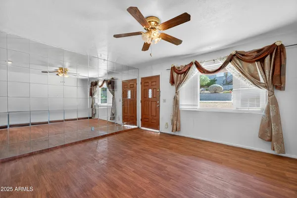 a view of an empty room with a ceiling fan and wooden floor