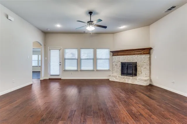 a view of an empty room with wooden floor fireplace and a window