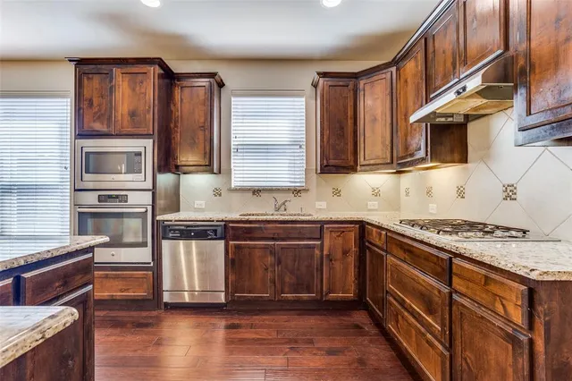 a kitchen with stainless steel appliances granite countertop a stove a sink and a microwave
