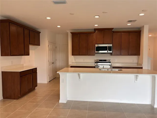 a large kitchen with stainless steel appliances a stove a sink a microwave and a refrigerator
