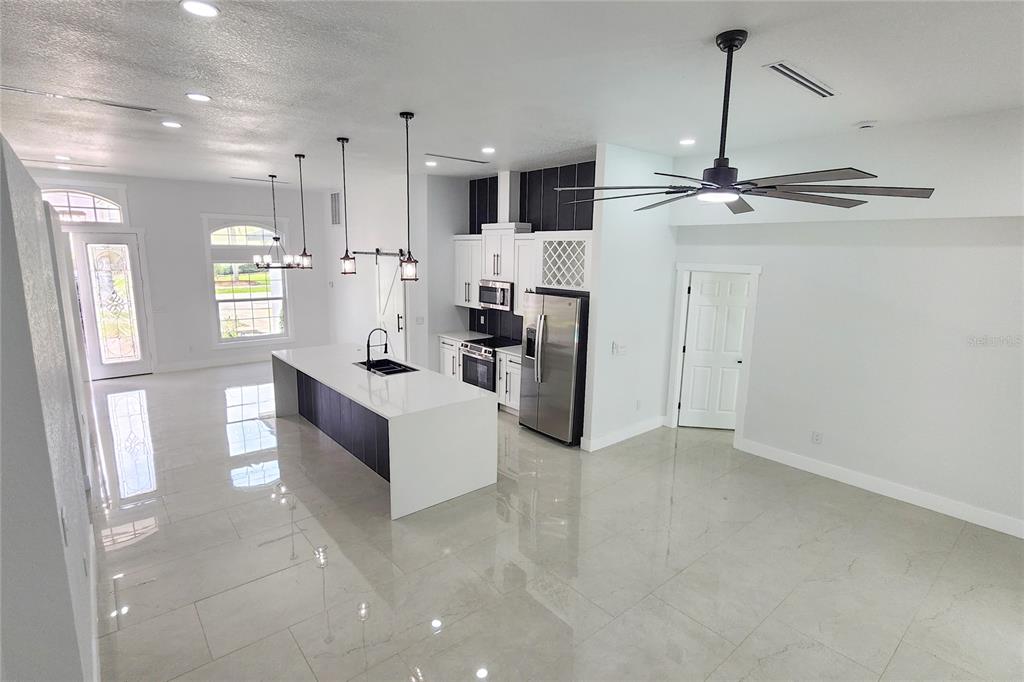 7027 Frascati Loop Wesley Chapel, FL 33544 - Photo 8 of 28 a living room with stainless steel appliances kitchen island furniture and a view of kitchen