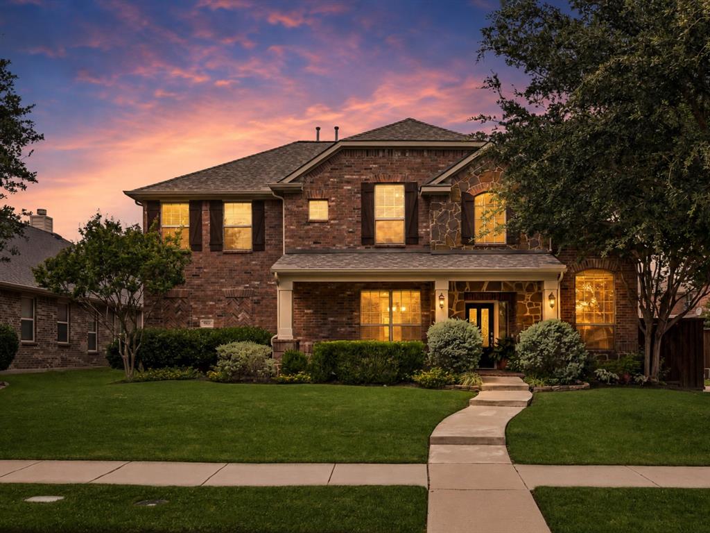 960 Remuda Road Frisco, TX 75033 - Photo 39 of 39 Brick and stone facade residence featuring a covered front porch with columns, a curved concrete walkway, a manicured lawn, and mature landscaping
