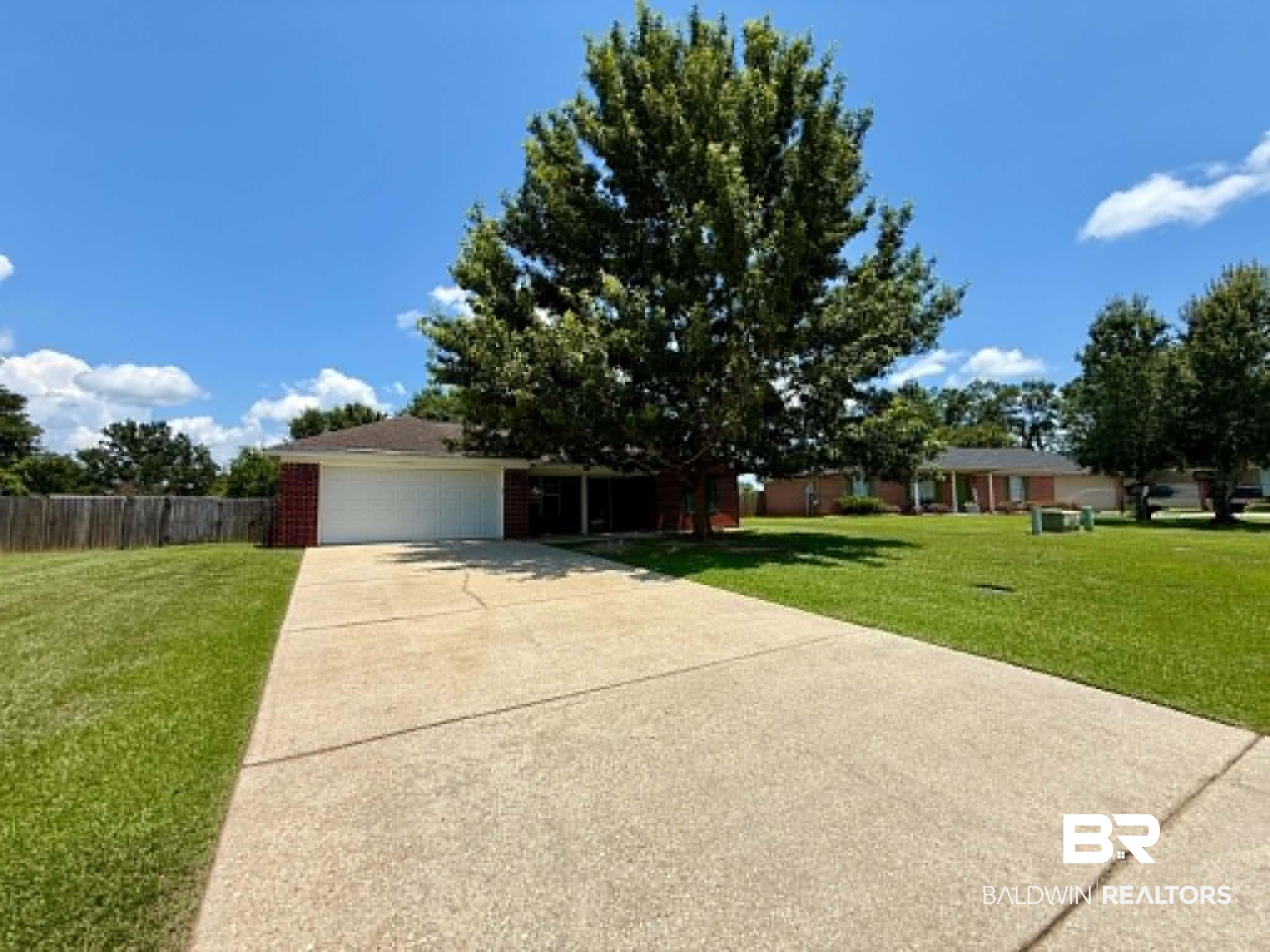123 Pennbrooke Loop Foley, AL 36535 - Photo 5 of 49 Brick veneer exterior with a prominent mature tree, concrete driveway, and attached garage