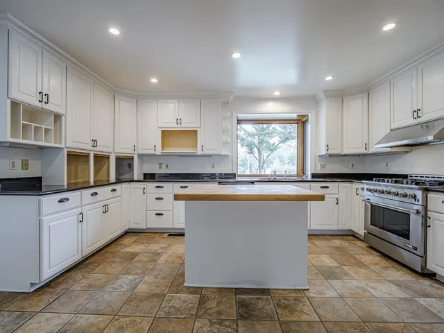 a large kitchen with stainless steel appliances granite countertop a stove a sink dishwasher and a refrigerator