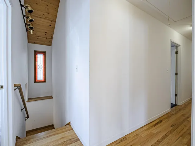 an empty room with wooden floor chandelier and windows