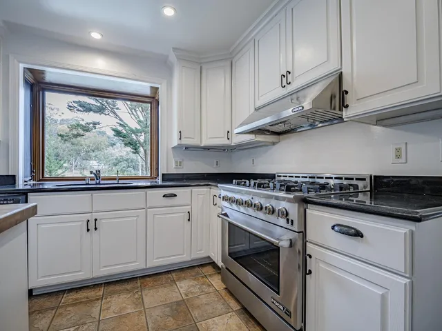 a kitchen with granite countertop white cabinets and white appliances