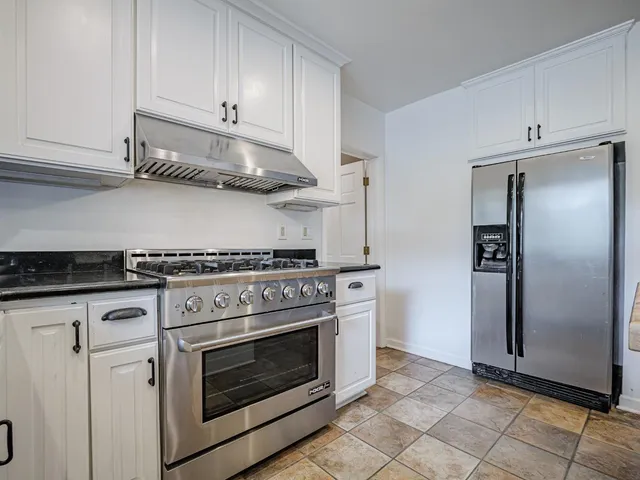a kitchen with stainless steel appliances granite countertop a stove a refrigerator and a cabinets