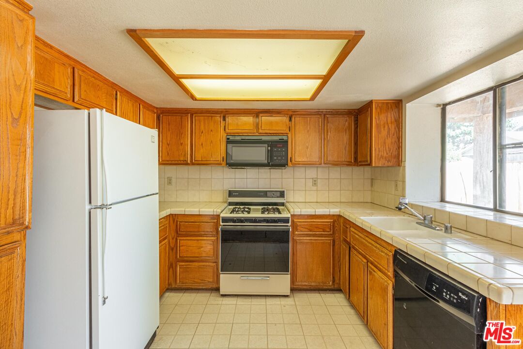 1217 Ave H4 Lancaster, CA 93534 - Photo 5 of 18 a kitchen with a sink a stove and refrigerator