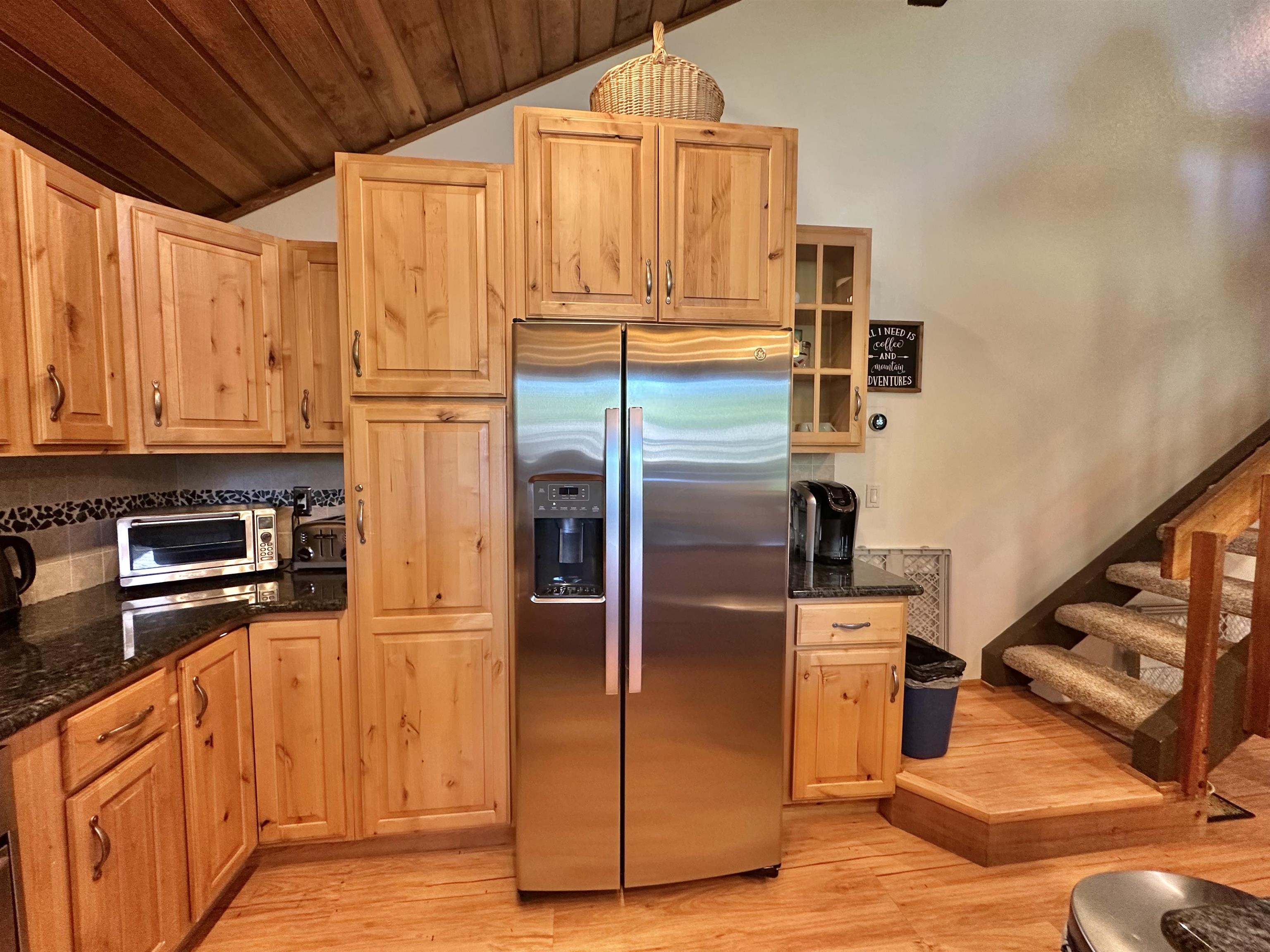 315 Fascination, Unit 315 Mammoth Lakes, CA 93546 - Photo 31 of 44 Kitchen featuring stainless steel French door refrigerator, natural wood cabinetry with curved hardware, dark speckled countertops, and a decorative tile backsplash