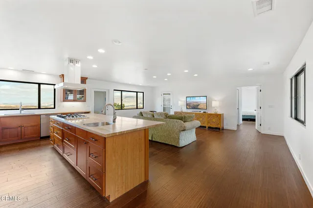 a large kitchen with kitchen island a stove a sink dishwasher and a dining table with wooden floor