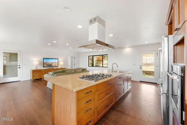 a kitchen with a stove a sink a refrigerator and a dining table with wooden floor