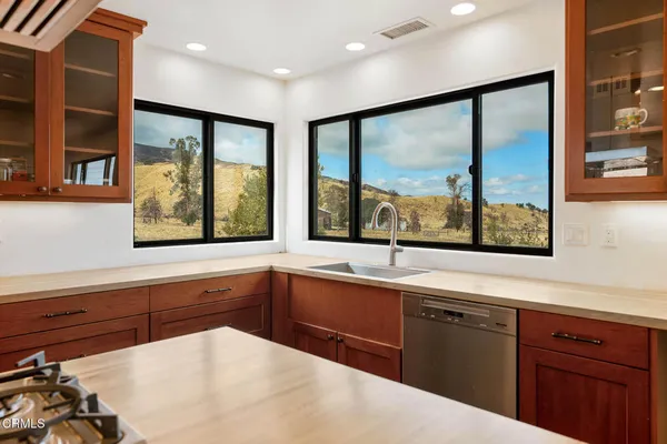 a kitchen with stainless steel appliances granite countertop a sink and a large mirror next to a window