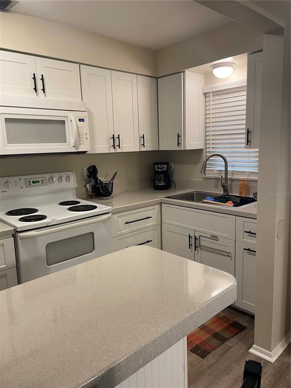 14531 Walsingham Road, Unit 203 Largo, FL 33774 - Photo 10 of 24 a kitchen with stainless steel appliances granite countertop a sink stove and cabinets
