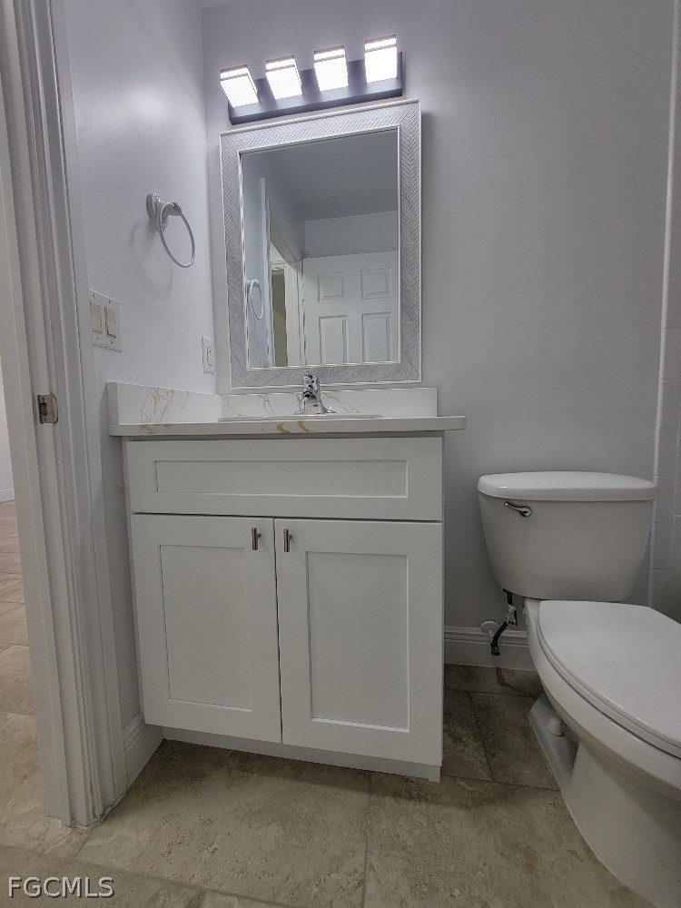 355 Paddock Street Lehigh Acres, FL 33974 - Photo 25 of 29 a bathroom with a toilet sink vanity and mirror