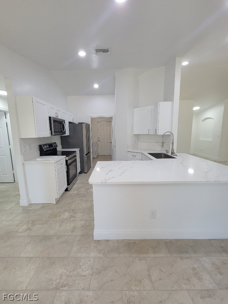 355 Paddock Street Lehigh Acres, FL 33974 - Photo 8 of 29 a large white kitchen with kitchen island stainless steel appliances cabinets a sink and a counter top space