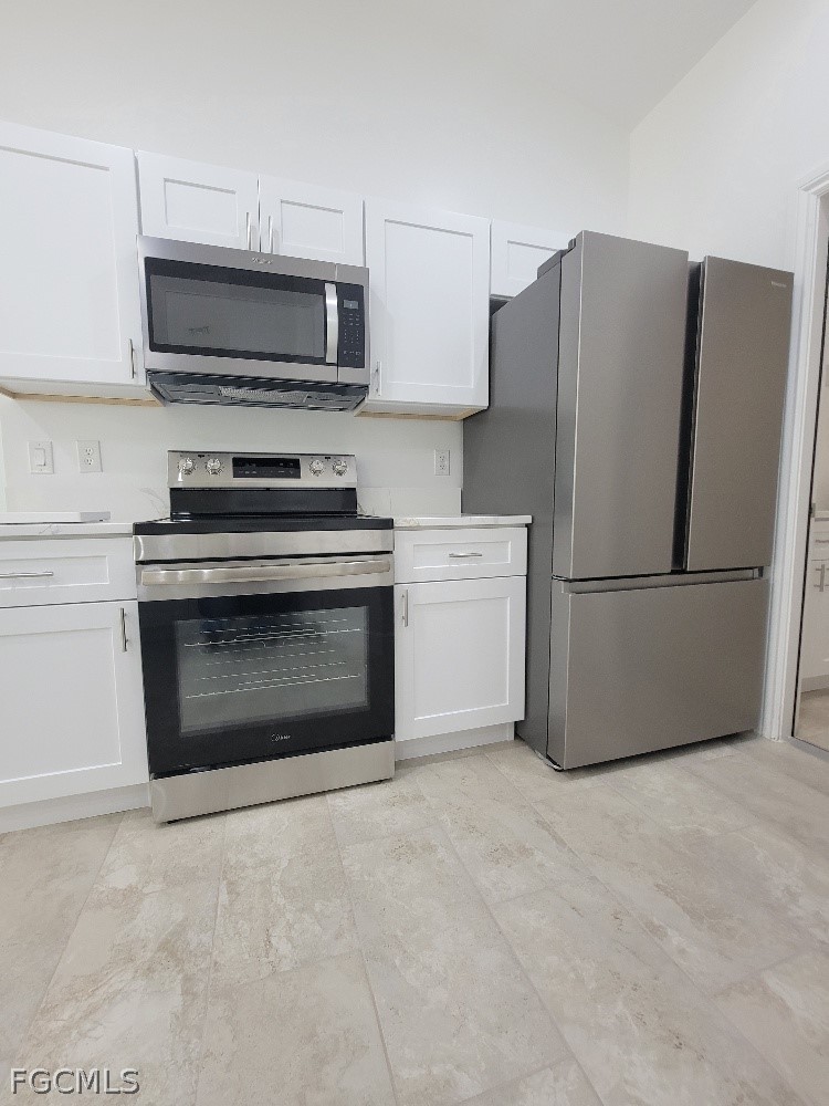 355 Paddock Street Lehigh Acres, FL 33974 - Photo 10 of 29 a kitchen with granite countertop a stove top oven a refrigerator and a fireplace