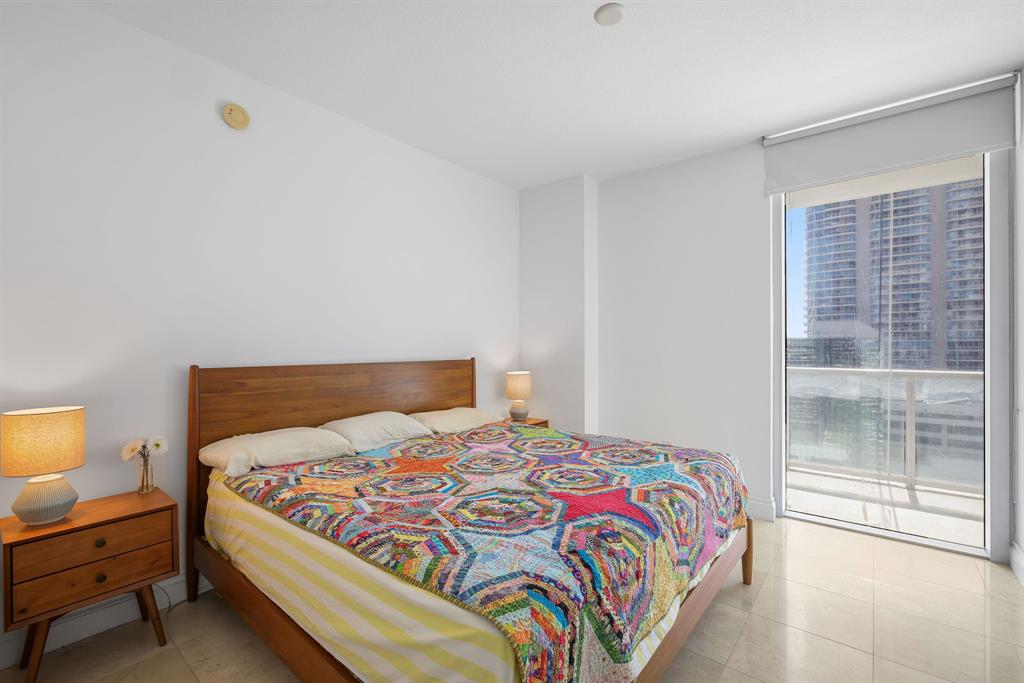 1050 Brickell Avenue, Unit 2302 Miami, FL 33131 - Photo 9 of 50 a bedroom with a bed and lamp with window