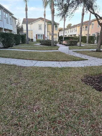 a view of a white house in a big yard with large trees
