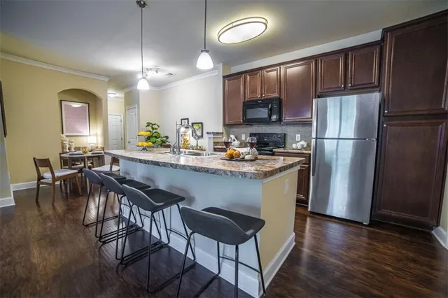 a kitchen with a refrigerator a stove a sink and a dining table with wooden floor