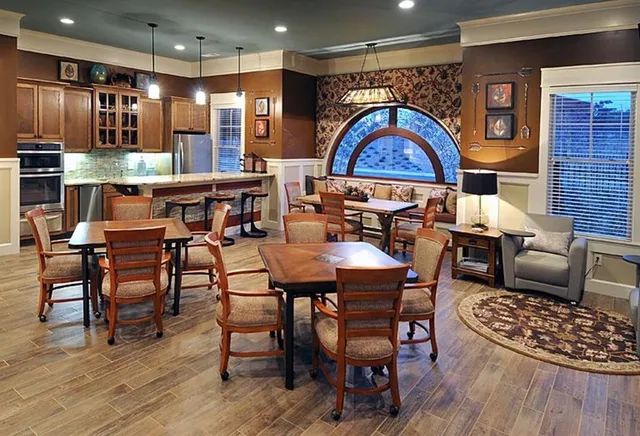 a dining hall with stainless steel appliances kitchen island a table and chairs