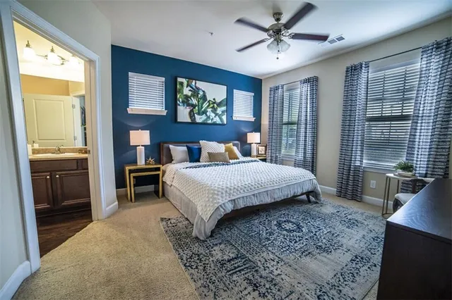 a bedroom with a large bed a chandelier and windows