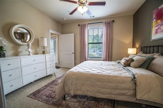 a bedroom with a bed a mirror on dresser and a window