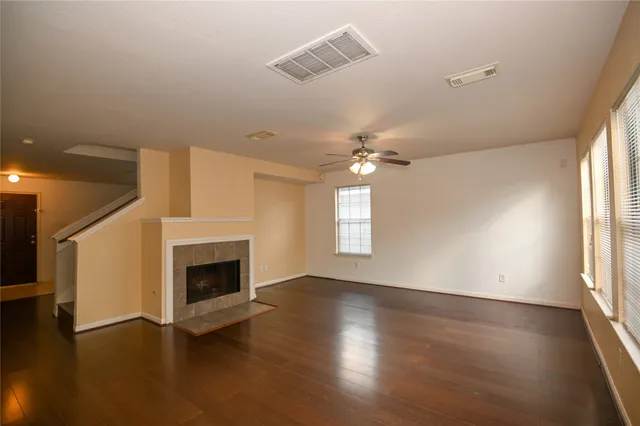 an empty room with wooden floor fireplace and windows