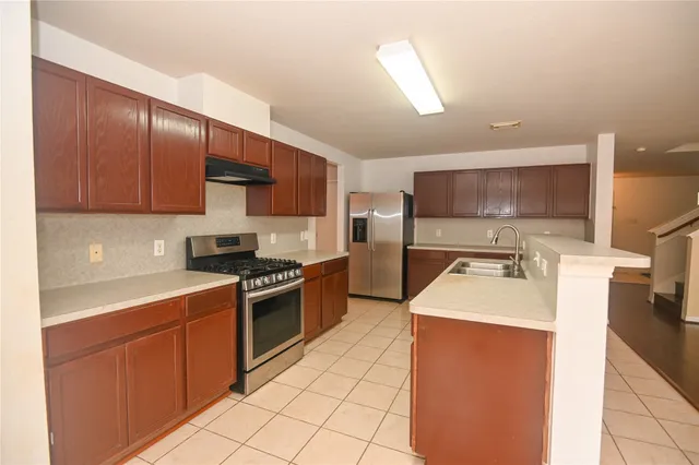 a kitchen with stainless steel appliances granite countertop a sink stove refrigerator and cabinets