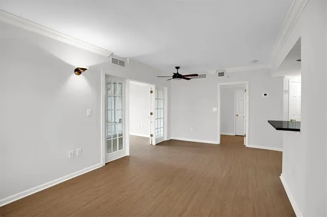 a view of an empty room with wooden floor and a ceiling fan