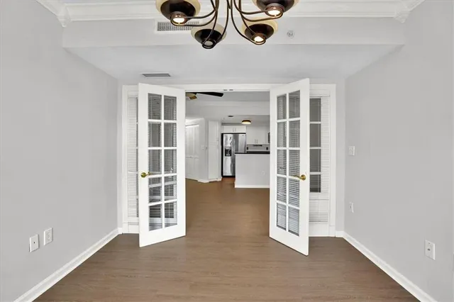 a view of an empty room with wooden floor and windows
