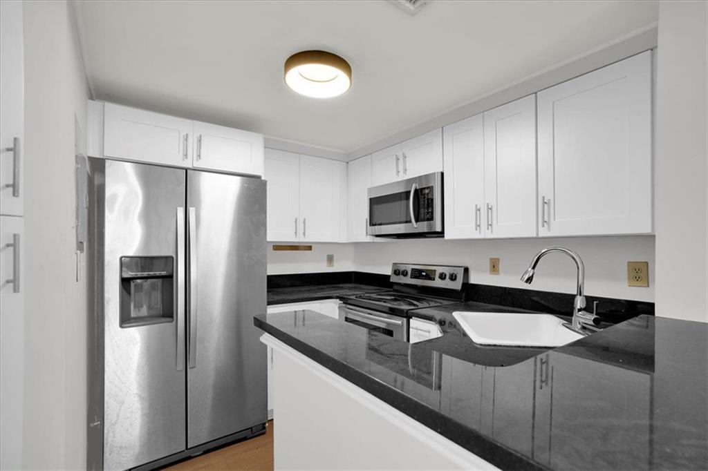 199 14th Street Northeast, Unit 2308 Atlanta, GA 30309 - Photo 9 of 35 a kitchen with stainless steel appliances granite countertop a sink a refrigerator a microwave a stove and white cabinets