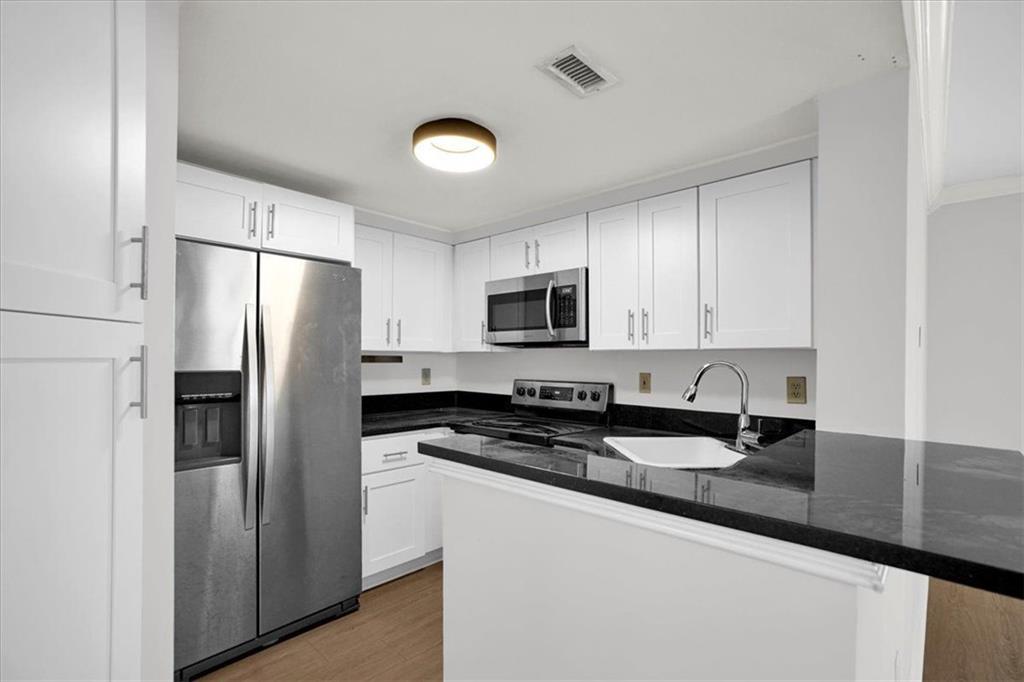 199 14th Street Northeast, Unit 2308 Atlanta, GA 30309 - Photo 10 of 35 a kitchen with stainless steel appliances granite countertop a refrigerator a sink a stove a microwave and white cabinets