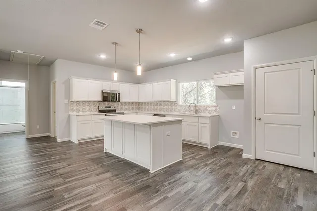 a kitchen with white cabinets and stainless steel appliances