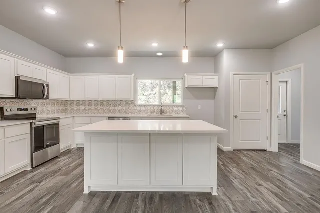 a kitchen with kitchen island a sink stainless steel appliances and cabinets